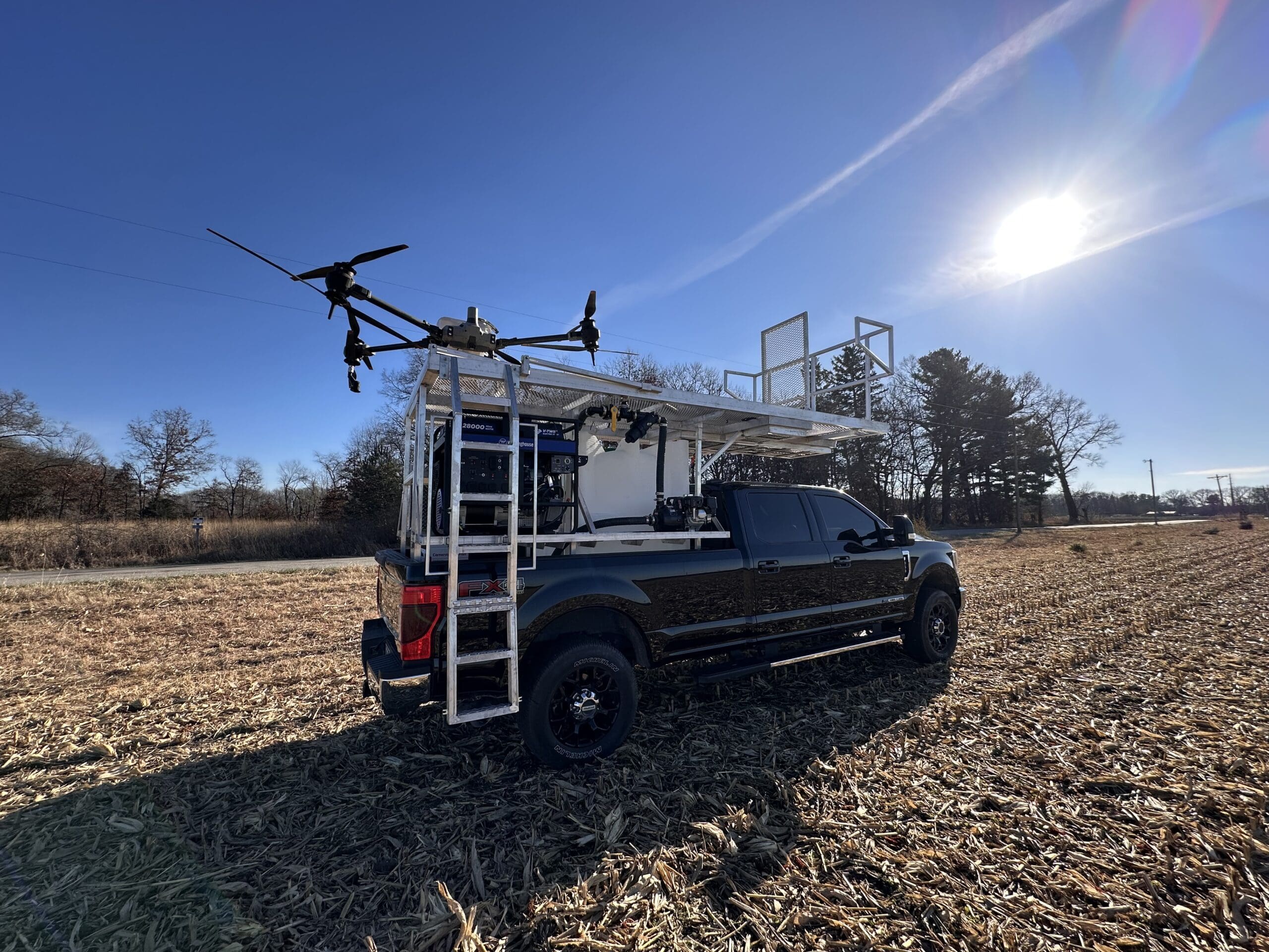 Heritage Drone Service agricultural drone mounted on a service truck, staged in a harvested field for precision drone spraying and seeding operations.